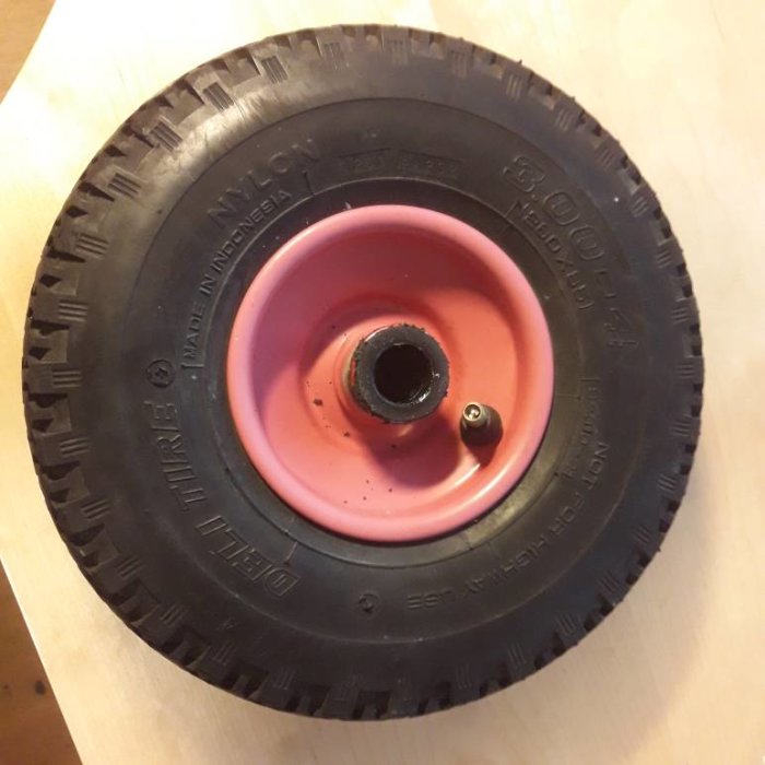 Slitet säckkärrsdäck monterat på en rosa fälg med kullager, sett ovanifrån.