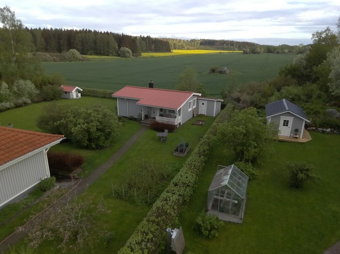 Renoverat enfamiljshus med utbyggd altan, uterum och spa-pool, omgivet av grönskande trädgård och fält.