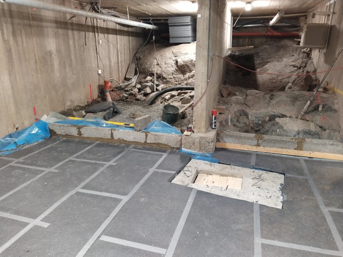Byggarbetsplats med stödmurar under konstruktion, delvis gjutna, och cellplastisolering vid pumpgrop.