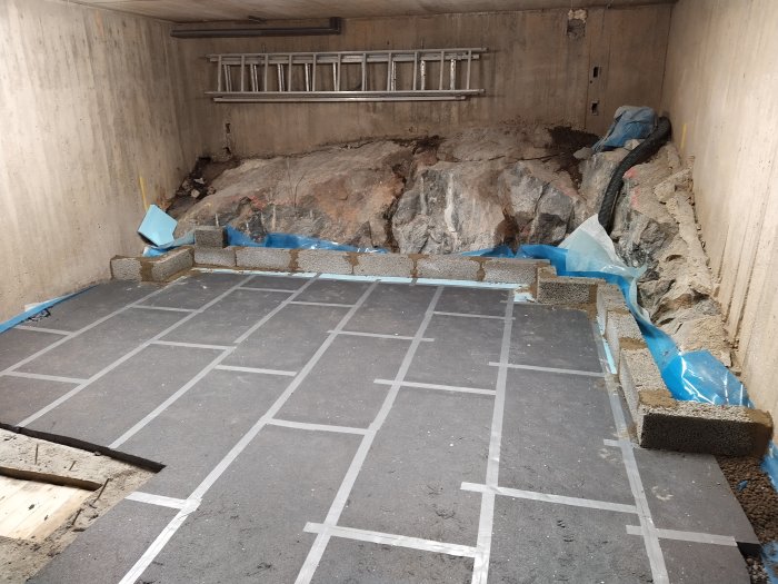 Grundläggning med cellplast och stödmurar inne i ett pågående byggprojekt, framsteg i bergrum.
