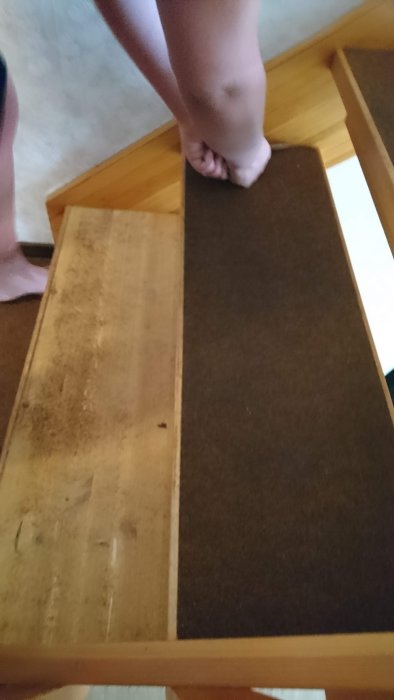 Fötter på en trappa där ena sidan visar en smutsig, obehandlad trappsteg och den andra en ren, täckt yta.