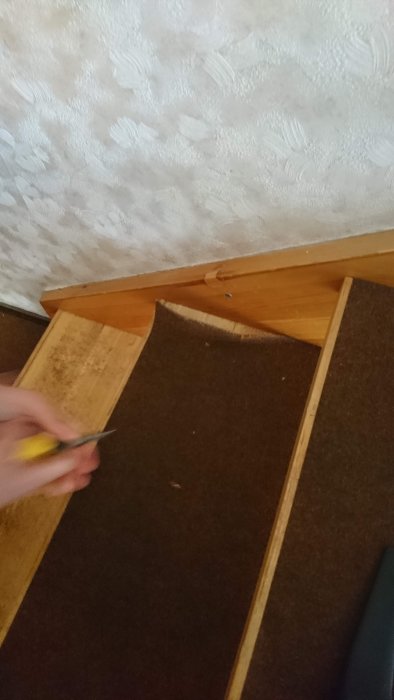 Förberedelse för golvlistmontering med en hand som håller en fogsvans sågandes av en trälist.
