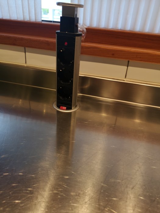 Pop-up eluttag i rostfritt stål på köksbänk.