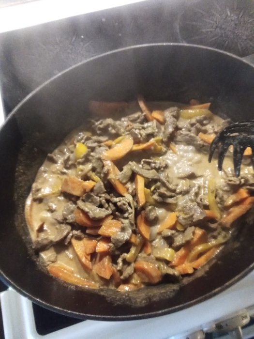 Tillagning av bonngryta med lövbiff, paprika, tomater, lök och morötter i en stekpanna.