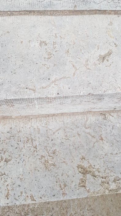 Närbild av steg i en entretrappa av ljus kalksten med variation i färg och textur.