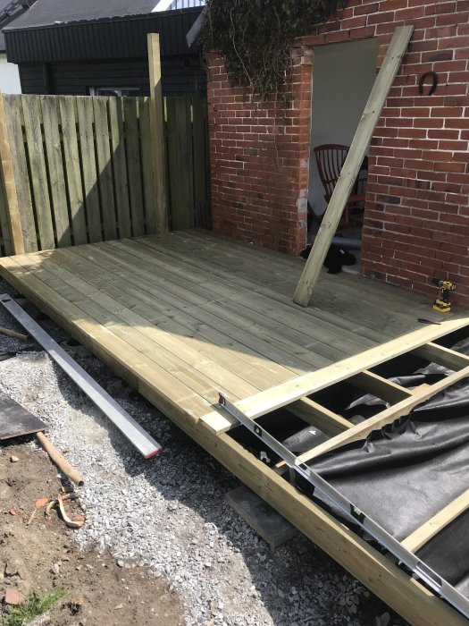 Pågående byggande av en träaltan med några brädor redan på plats och byggmaterial synligt.
