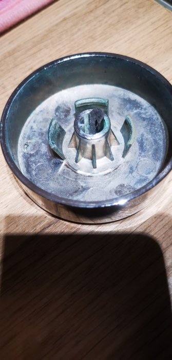 En trasig metallisk komponent på ett träbord.