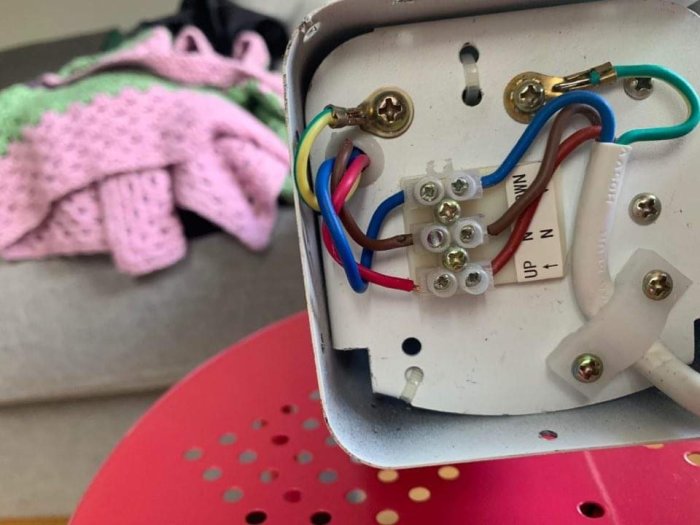 Närbild på en öppen elektrisk anslutningsdosa med färgkodade kablar och anslutningsklämmor.
