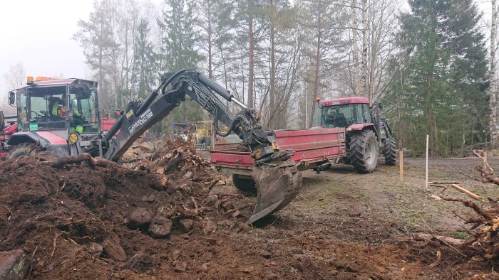 Grävmaskin och traktor på byggarbetsplats med jordhögar och omrörda markområden.