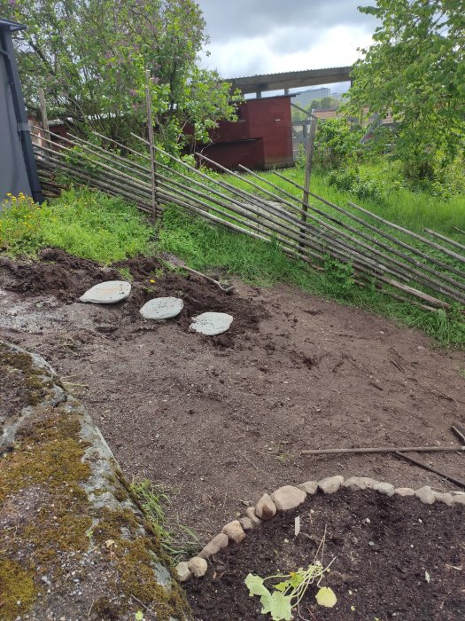 Starten av anläggning av trappa med markerade steg i en grässlänt, gammalt staket i bakgrunden.