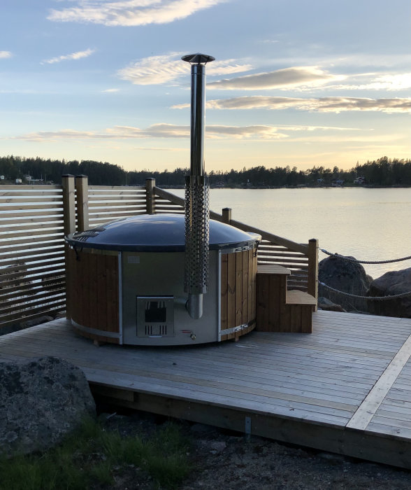 En badtunna på en trädäck vid vattnet i skärgården med skymmande himmel i bakgrunden.