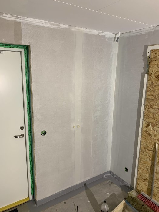 Renoverat hörn i badrum med spacklade väggar och installerat tätskikt klar för målning.