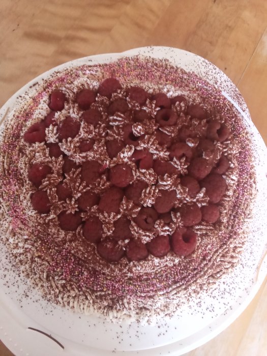 Enkel morsdagstårta dekorerad med hallon, grädde och strössel.