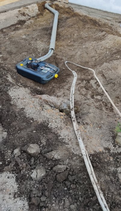 Grävningsarbete för uteplats med synliga gamla oljerör och uppriven mark.