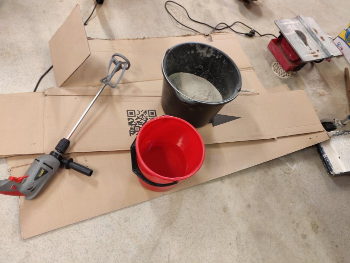 Verktyg för kakling med omrörare, hink, balja med kakelfix och kakelsåg på skyddspapp.
