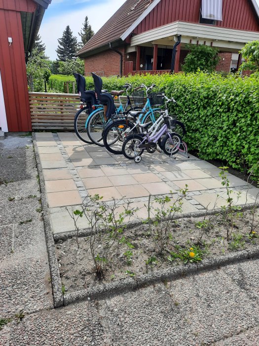 Cyklar låsta vid nytt cykelställ utanför rött hus, försök att förhindra stöld.