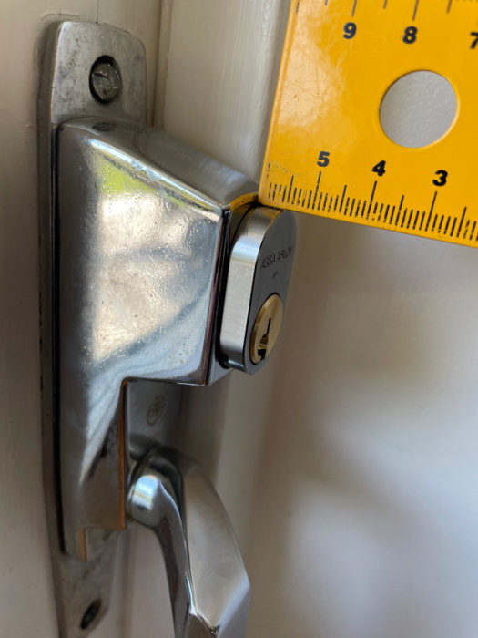 Mätning av ett låscylinderutstick på en dörr med skjutmått visande ca 32 mm.