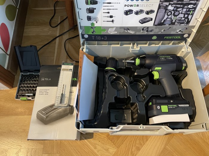 Ny Festool borrskruvdragare med batteri och laddare, sats med bits och instruktionsbok, på ett köksgolv.