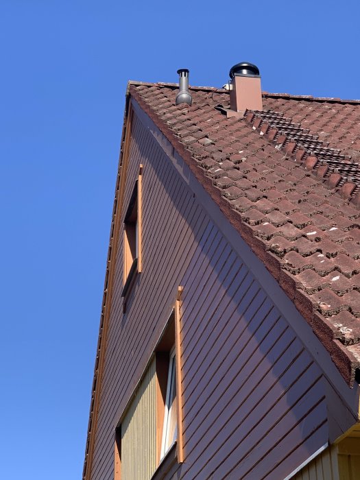 Toppvåning på hus med tegeltak och ventilationsrör.