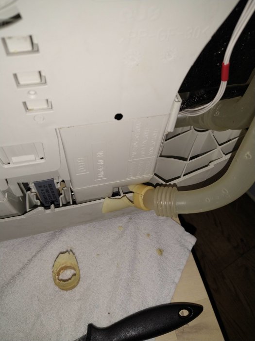 Reparerad Miele diskmaskin med ny slang och slangklämmor, delvis isärmonterad på ett vitt handduk.