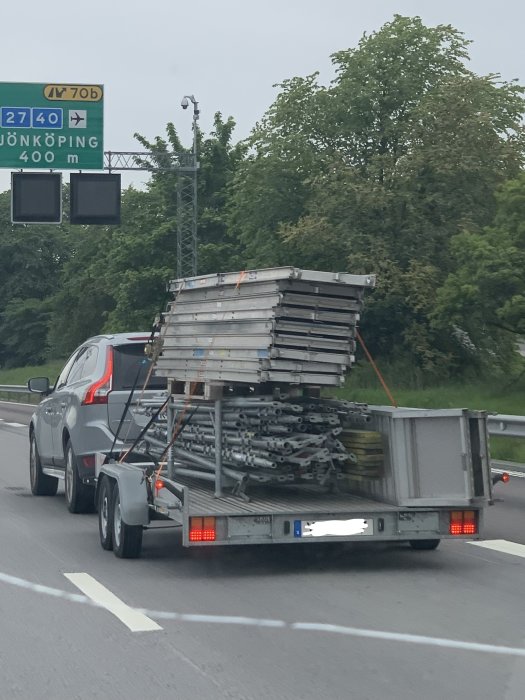 Bil som drar ett släp lastat med byggställningsdelar på E6 i Göteborg.