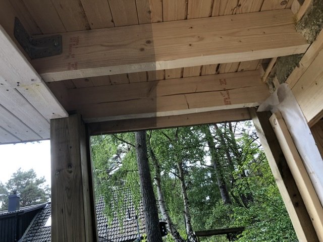 Nytt tak i konstruktion, med synliga klädselbrädor och bjälkar, utomhus träd i bakgrunden.