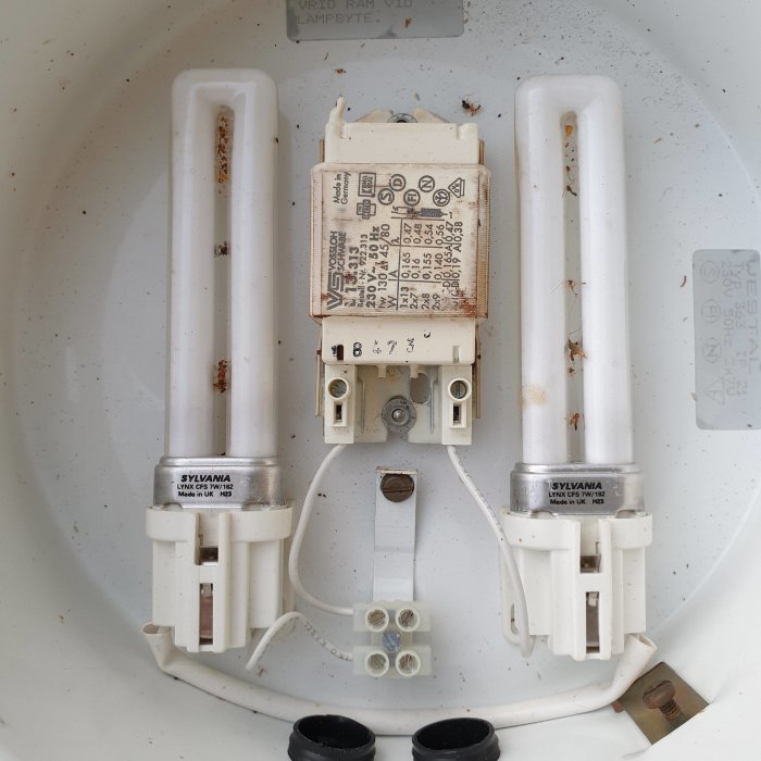 En fasadarmatur med två lysrör och en anslutningsdosa, gamla kabelklämmor på höger sida.