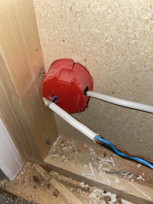 Infälld röd dosa med elektrisk kabel i en väggkonstruktion.