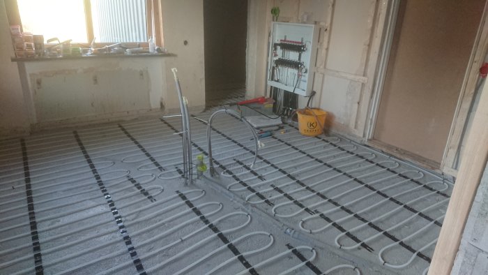 Renoveringsprojekt av ett kök med nyinstallerade golvvärmeslangar och elinstallationer synliga på betongplatta.