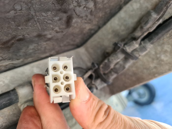 Hand håller en kontakt för släpvagnsbelysning.