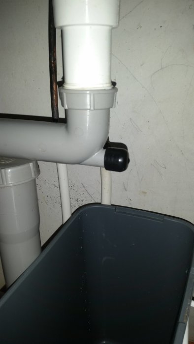 Vit avloppsrör under vasken med en svart slanganslutning som inte passar på röret.