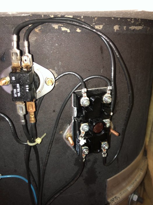 Elkopplingspanel med ledningar och säkringskomponenter på en brun bakgrund.