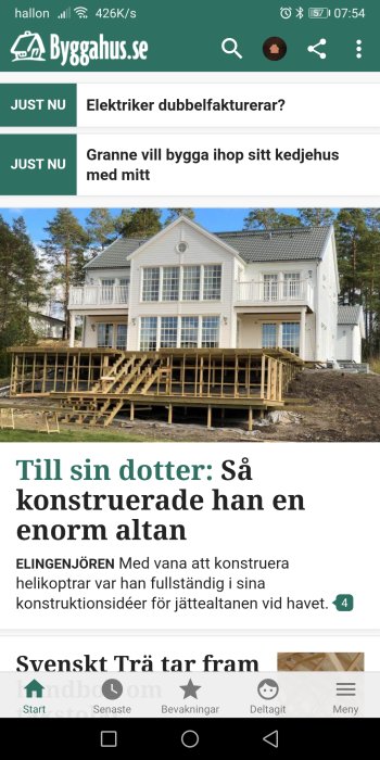 Vit villa med konstruerad stor altan under byggnation framför en skogsbakgrund.