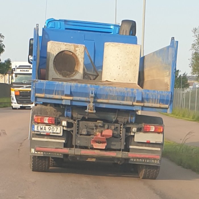 Lastbil med osäkrade betongklumpar på flaket, parkerad på en gata.