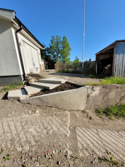 Obyggd garageuppfart med betongkanter och grus, redo för markstensbeläggning.