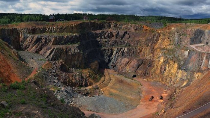 Stor gruvöppning i landskapet med färgrika mineralavsättningar, vilket visar miljöpåverkan från kopparutvinning.