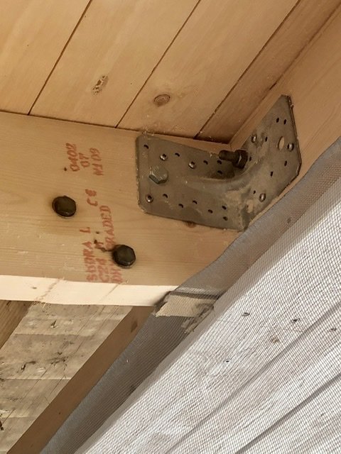 Infällda 100x100 träbjälkar i taket förstärkta med metallvinkel och franska bultar för hängstolar eller soffa.