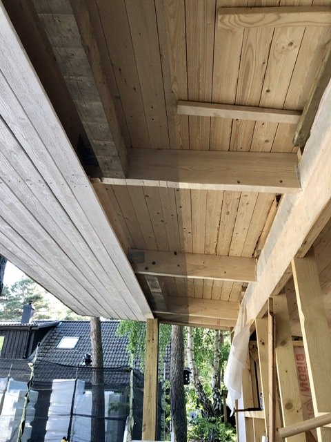 Träbjälkar och takkonstruktion med infällda 100x100 bjälkar för hängstolar eller soffa.