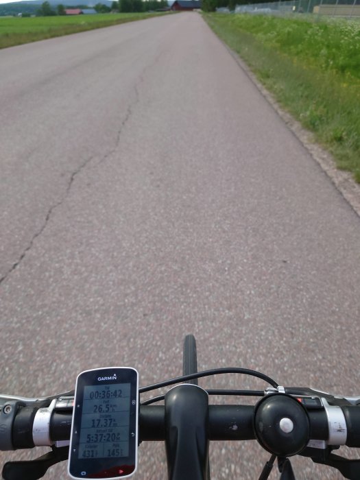 Cykelstyre med en GPS-cykelcomputer visande hastighet och distans på en landsväg.