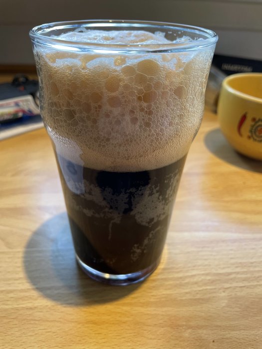 Ett glas mörk porteröl med tjockt skum upplyst av bordets belysning.