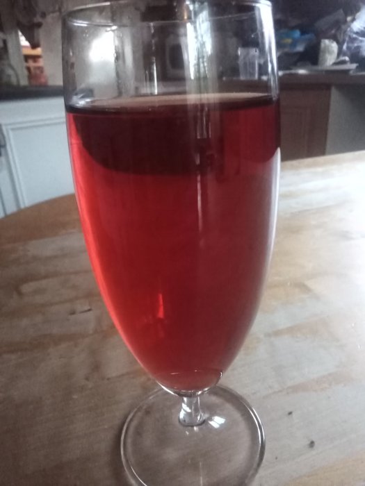 Ett glas med röd dryck som står på ett träbord, refererat till som "Lapplands rubin".