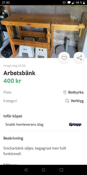 Begagnad snickarbänk i trä till salu, placerad i ett garage, med verktygshyllor under.