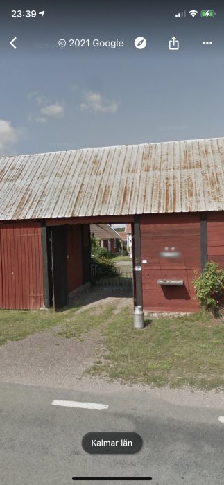 En traditionell röd ladugård med öppen port som leder in till en bostadsgård.