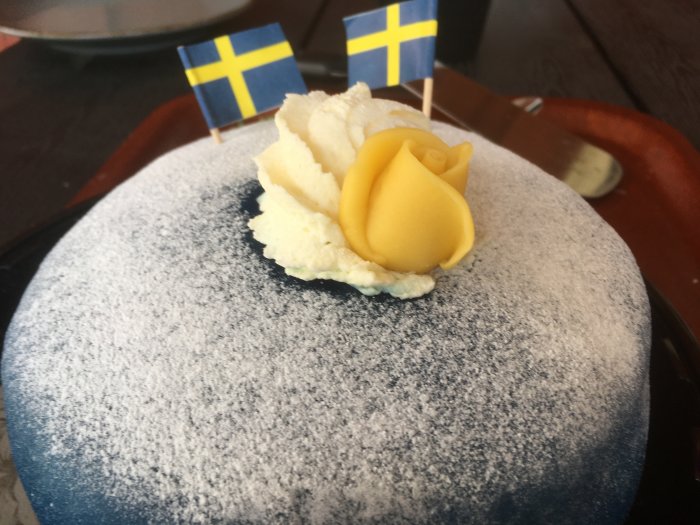 Nationaldagstårta med svensk flagga och gul marsipanros, firande av bröllopsdag.