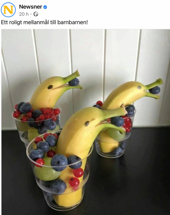 Kreativa mellanmål av bananer formade som delfiner och fyllda glas med bär och frukt.