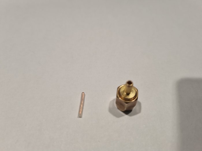 SMA-J-1.5 RF koaxialkontakt och del av kabel på vit yta.