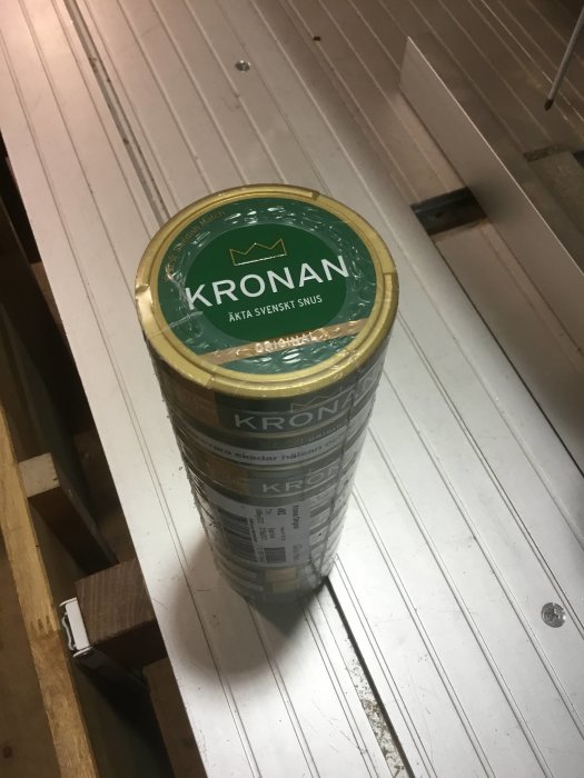 En dosa Kronan snus på ett vitmålat trägolv.