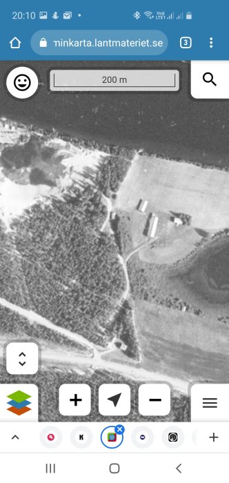 Svartvit flygbild från 70-talet över landsbygd med byggnader och vägar, en avgrävd väg ej synlig.