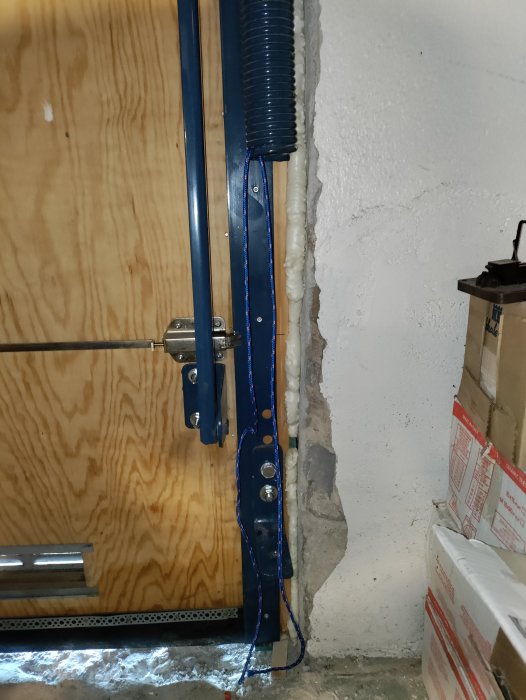 Monterad Edsbyporten vipport i garage med en blå fjäder, snöre knytet runt och omonterad m12-bult.