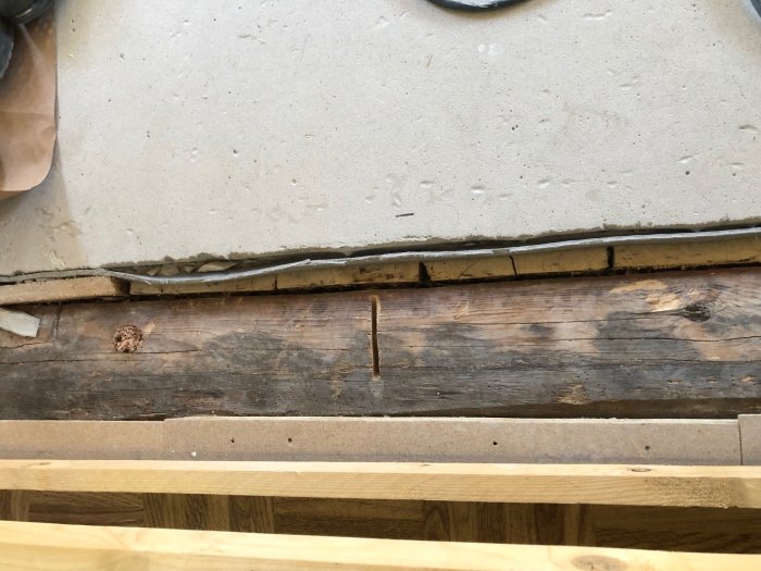 Öppning mellan ny betonggrund och gammal torpargrund med synlig ojämn syll i ett renoveringsprojekt.